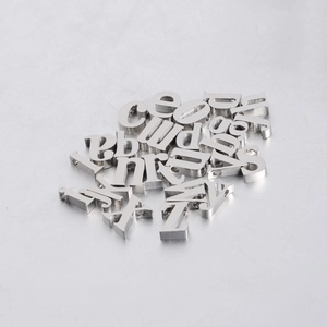 Macro shot of polished 10mm stainless steel alphabet beads with letter hole details