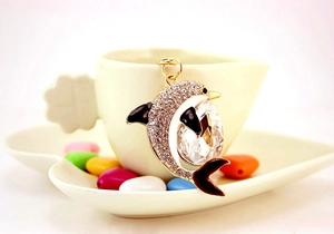 Detailed view of crystal dolphin keychain with rhinestones on a ceramic cup handle