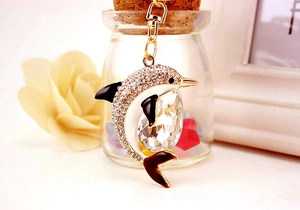 Close-up of crystal dolphin keychain with gold plating and white enamel details