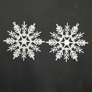 Detailed view of two white plastic snowflake ornaments on a black textured background