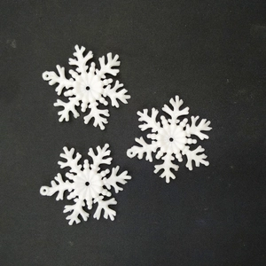 Close-up of three white plastic snowflake ornaments for DIY Christmas decorations