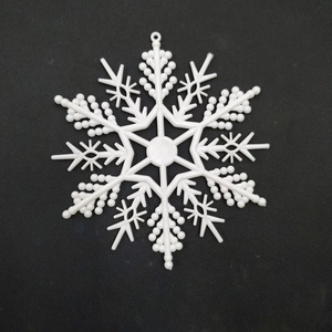 Detailed top-down view of a white plastic snowflake ornament on a black background