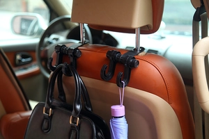 Dual car seat back hook holding a leather handbag and umbrella for interior storage
