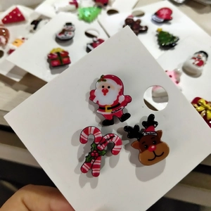 Close-up of Santa Claus, reindeer, and candy cane acrylic Christmas pins on card
