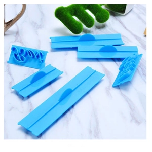Blue plastic cake stamps with Best word mold on white marble background for baking
