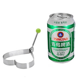 Heart-shaped stainless steel fried egg mold with green handle next to a beverage can