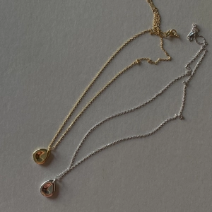 Polished gold and silver teardrop pendant necklaces in minimalist mirror finish detail