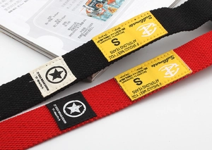 Detailed flat lay of children's canvas belts in black and red with decorative fabric labels