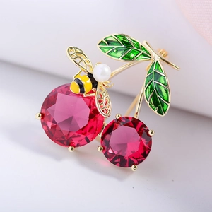 Macro shot of red gemstone cherries with green enamel leaves and small bee pearl detail