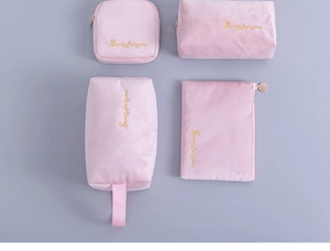 Detailed set of four pink velvet makeup bags with gold embroidery and metal zippers