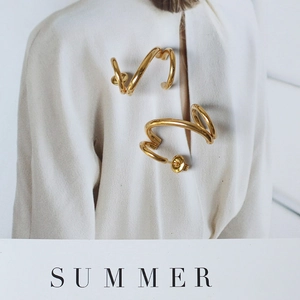 Close-up of 18K gold-plated twisted spiral stud earrings on a fashion magazine