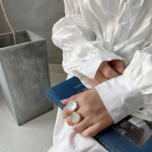 Close-up of gold and silver shell rings with twisted rope texture on a hand