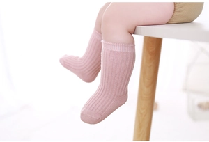 Close-up of baby wearing pink ribbed knit cotton warm crew socks on white table