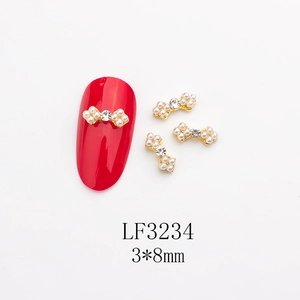 Vue macro d'un bijou d'ongle nœud 3x8mm avec perle et strass sur un ongle rouge