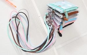 Detail of colorful PU leather coin purses with daisy patterns and braided lanyards