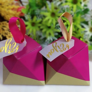 Macro shot of pyramid-shaped rose red and gold wedding favors with elegant silk ribbons