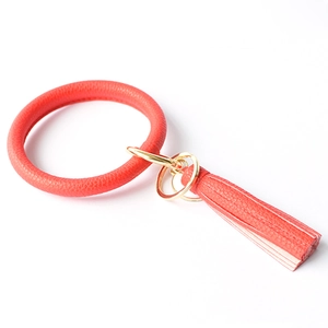 Detail showing red textured leather wristlet keychain with gold metal ring and tassel