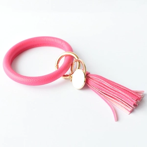 Detailed view of pink leather O-ring keychain with golden hardware and fringe tassel