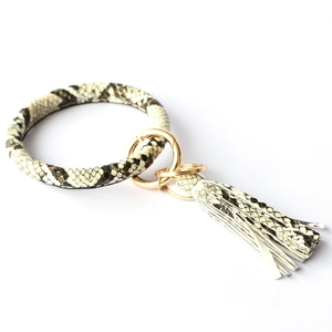 Detail of round snakeskin pattern keychain with leather tassel and gold metal ring