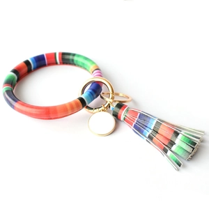 Detail of colorful striped leather tassel keychain bracelet with golden metal ring and charm