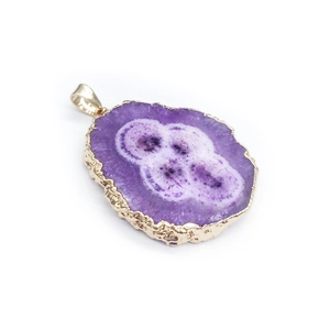 Macro view of purple agate slice pendant with gold-plated textured edges on white background