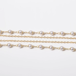Macro detail of golden chain links with white imitation pearls for elegant Y-necklaces