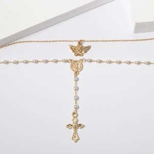 Detail shot of golden vintage angel pendant and crucifix tassel on a pearl Y-necklace