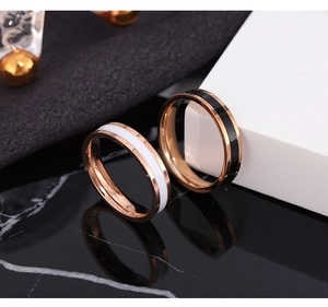 Detail of rose gold couples rings with black and white enamel inlays on marble