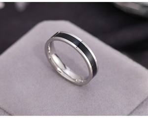Close-up of a silver stainless steel ring with black enamel inlay in a jewelry box