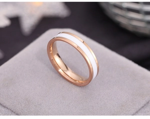 Detailed close-up of rose gold stainless steel ring with white enamel inlay on velvet