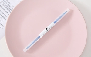 Close-up view of a blue double-ended highlighter pen placed on a pastel pink plate