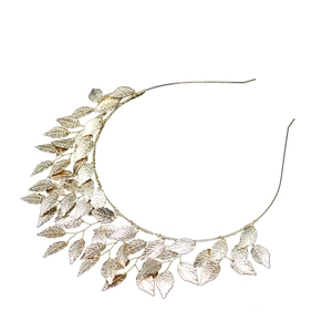 Close-up detail of golden alloy leaf headband with metallic wire texture on white background