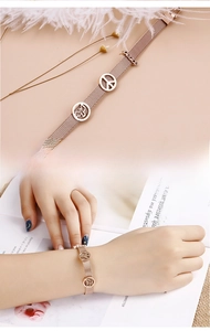 Detail eines roségoldenen Mesh-Armbands mit Friedenszeichen und Schmetterlingsanhängern