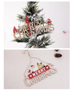 Detail of laser-cut Merry Christmas wooden ornament hanging on a festive tree branch