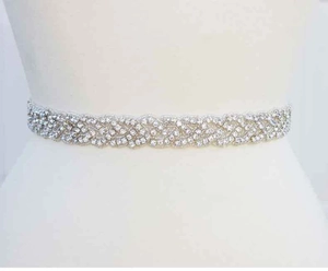 Macro detail of wave-patterned silver wedding belt with sparkling crystals on white dress
