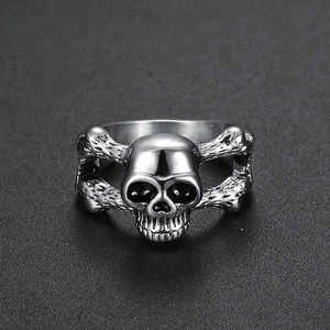 Detail of silver stainless steel skull and crossbones ring on black textured background