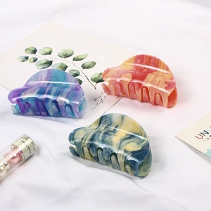 Detail of marble pattern acetate hair claws in purple, red, and dark green with glitter