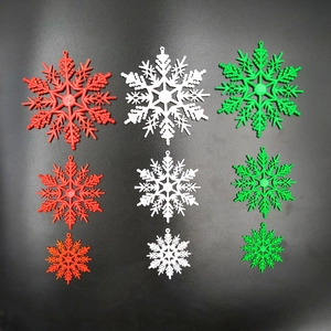 Flat lay of red, white and green plastic snowflake ornaments in three different sizes