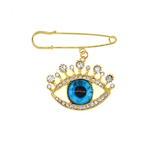 Detailed view of evil eye brooch with blue stone, gold plating, and sparkling rhinestones