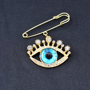 Detailed view of evil eye brooch with blue stones and clear crystals on golden pin