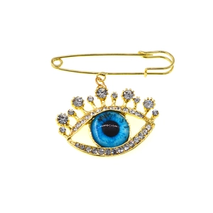 Elegant gold safety pin brooch featuring a blue evil eye pendant with sparkling crystals