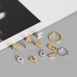Detailed view of S925 silver alphabet charms with cubic zirconia on neutral backdrop