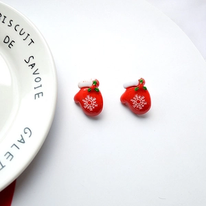 Detail of red Christmas glove earrings with white snowflakes on white porcelain plate