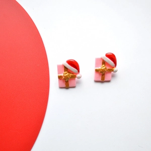 Close-up of handmade pink Christmas gift box earrings with red hats and gold ribbons