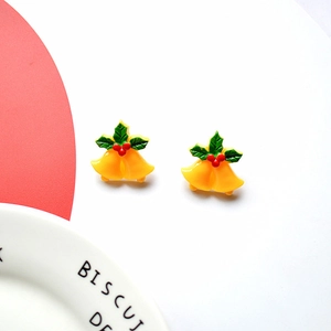 Close-up of yellow Christmas bell earrings with green leaves and red berry details