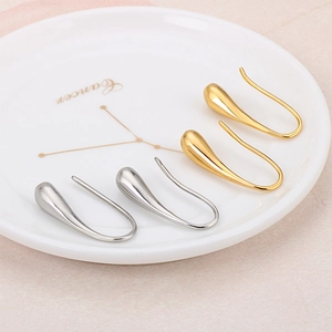 Minimalist gold and silver waterdrop earrings displayed on a white decorative plate