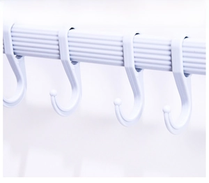 Detail of white S-shaped plastic hooks with protective round tips on a non-slip bar