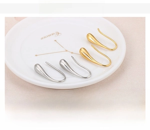 Detailed view of teardrop hook earrings in polished gold and silver stainless steel