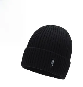 Detail of black knitted beanie featuring folded cuff and white logo brand patch