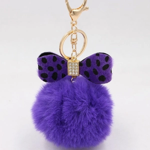 Detail of purple faux fur pompom keychain with leopard print bow and gold hardware